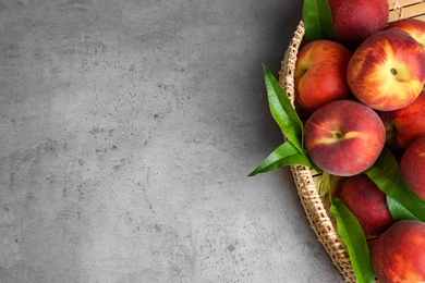 Photo of Wicker tray with tasty peaches on grey table, above view. Space for text