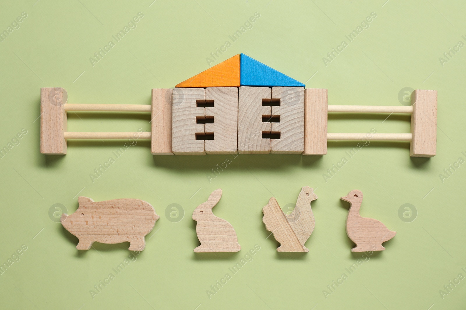 Photo of Set of wooden building and animals on pale light green background, flat lay. Children's toy