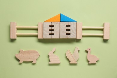 Photo of Set of wooden building and animals on pale light green background, flat lay. Children's toy