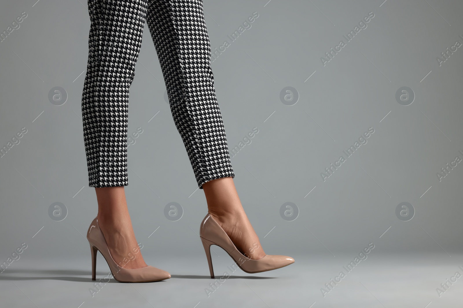 Photo of Businesswoman in beige shoes on grey background, closeup. Space for text