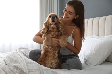 Young woman and her English Cocker Spaniel on bed indoors. Pet friendly hotel