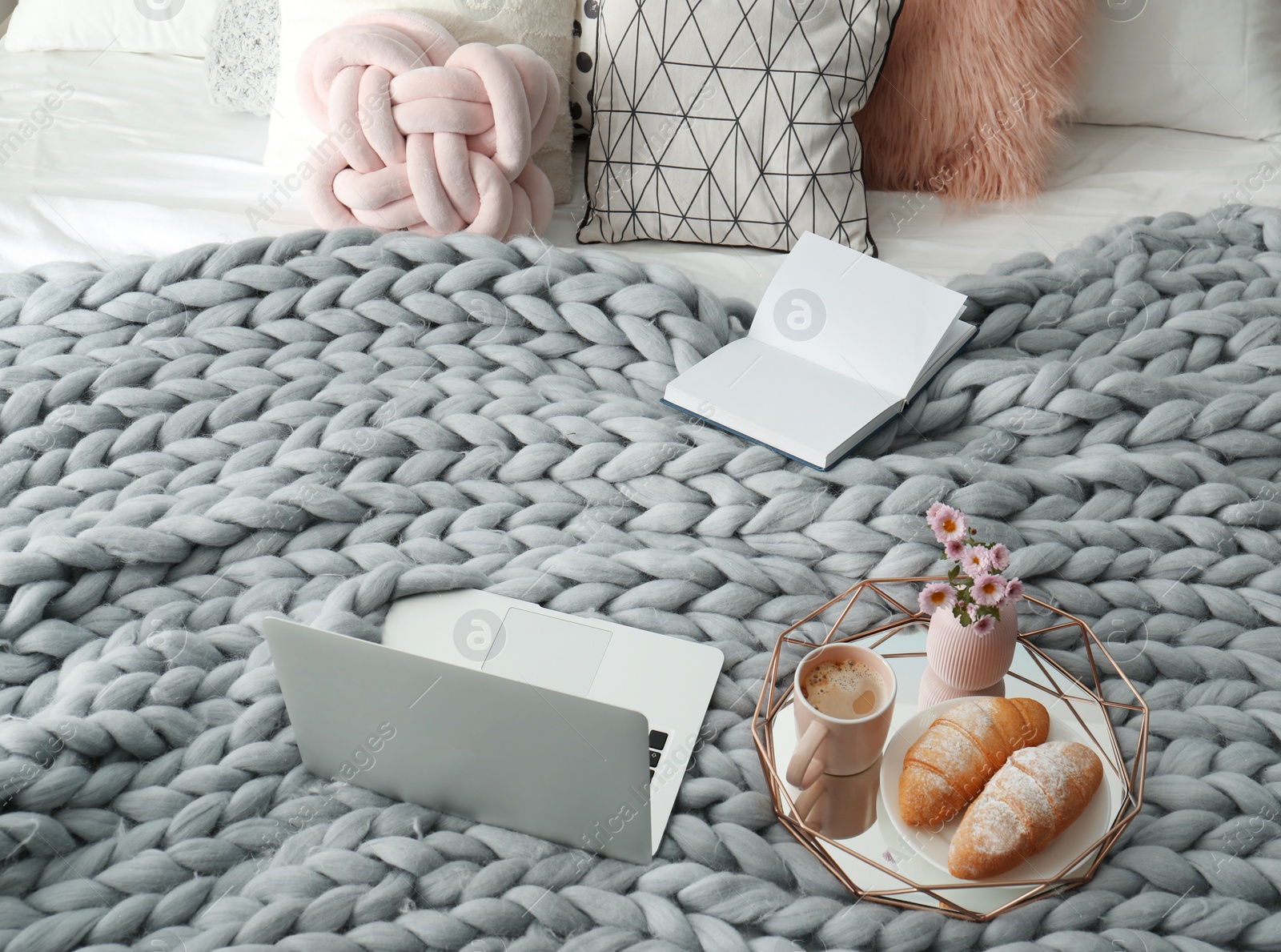 Photo of Tray with tasty breakfast, laptop and book on bed