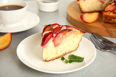 Photo of Slice of delicious cake with plums on light table, closeup