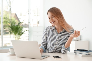 Photo of Young businesswoman using laptop at table in office