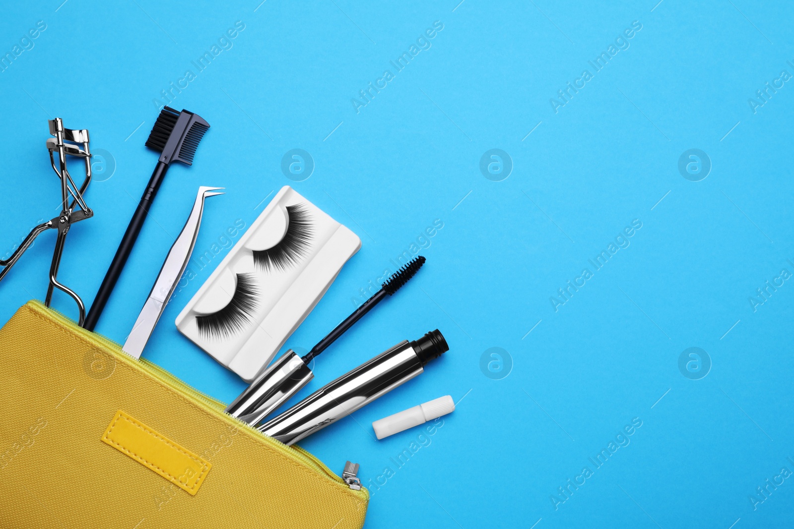 Photo of Flat lay composition with fake eyelashes, mascara brush and tools on light blue background. Space for text