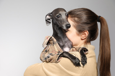 Photo of Young woman with her Italian Greyhound dog on light background