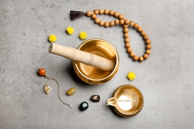 Flat lay composition with golden singing bowl on grey table. Sound healing