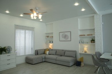 Photo of Comfortable furniture, ceiling fan and accessories in stylish living room