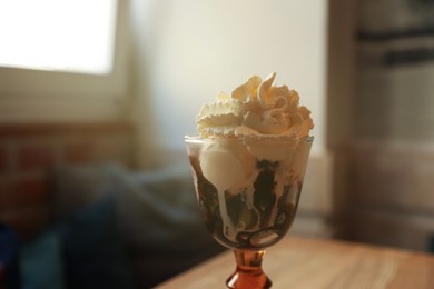 Delicious dessert with whipped cream in glass on table indoors, closeup