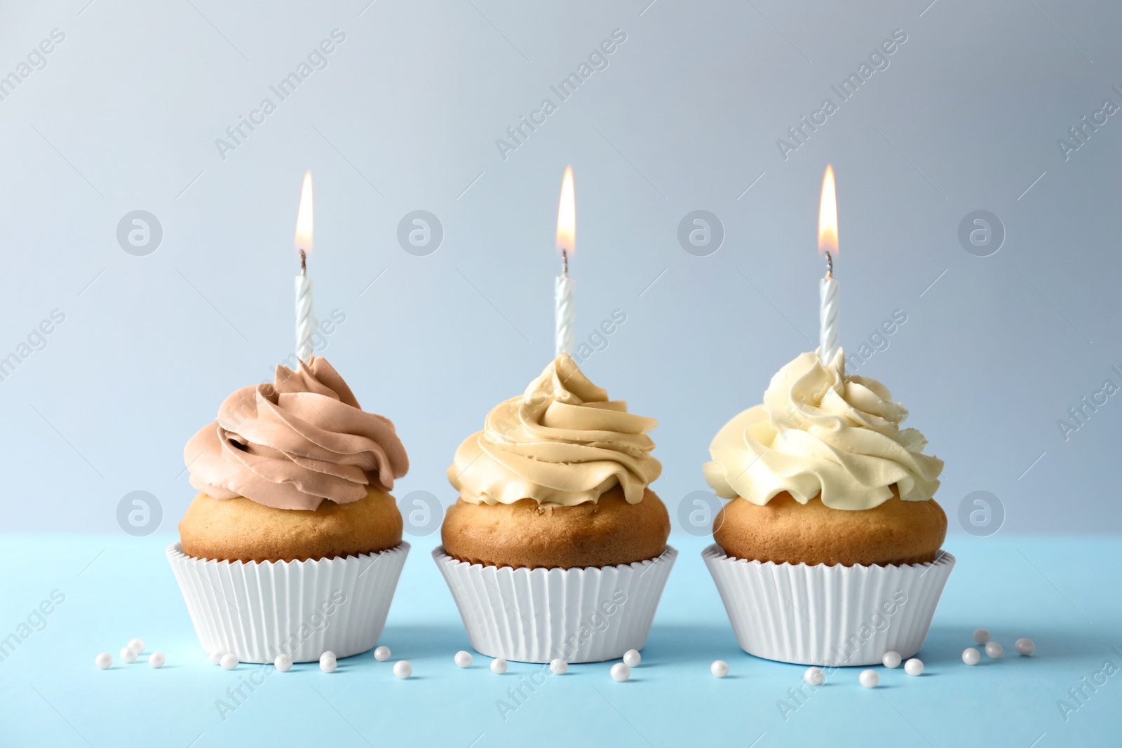 Photo of Delicious birthday cupcakes with candles on light background