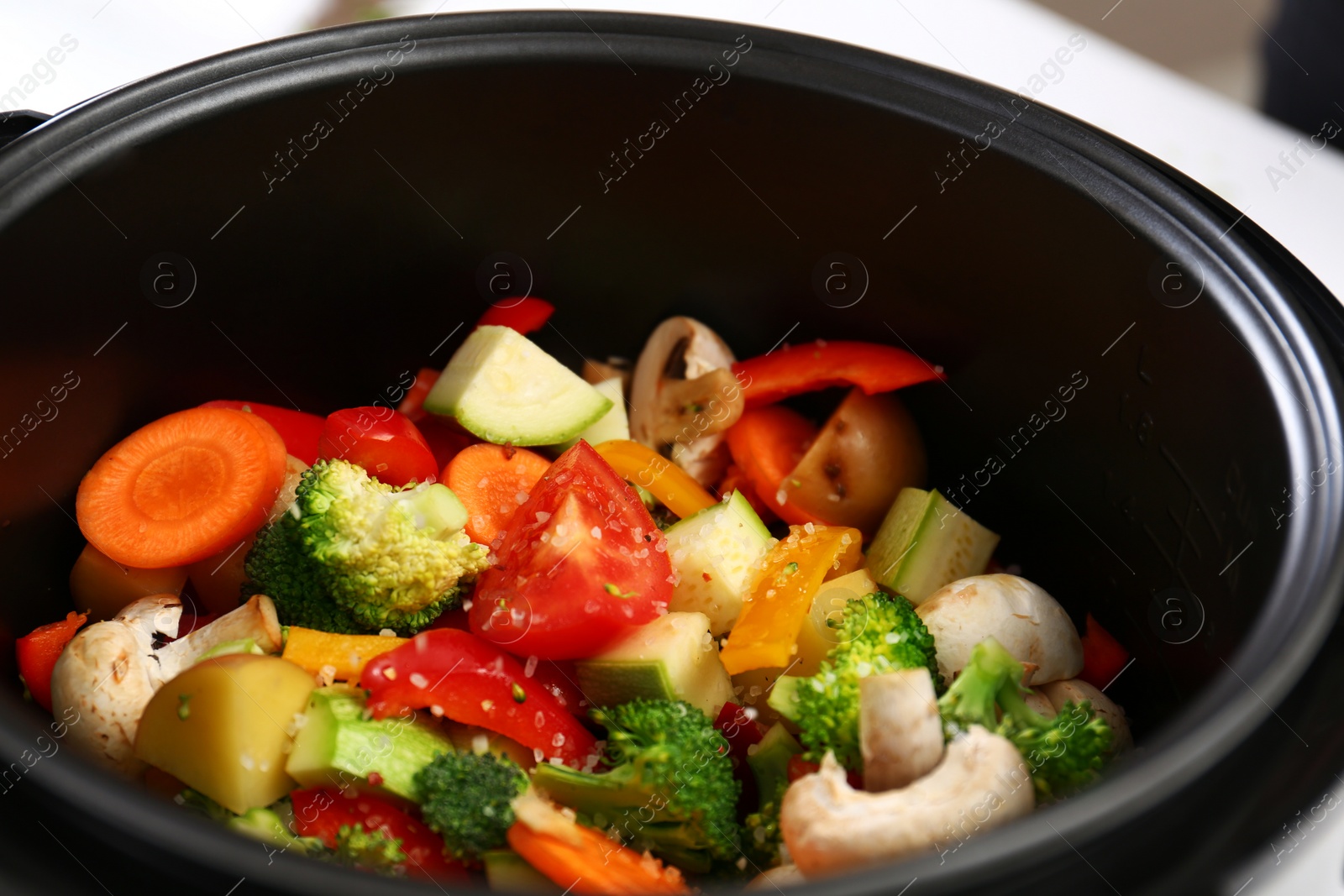 Photo of Adding salt to vegetables in multi cooker, closeup