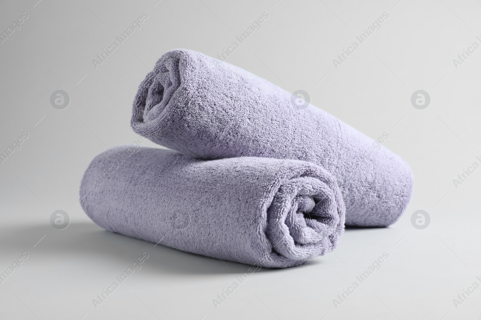 Photo of Fresh fluffy rolled towels on grey background