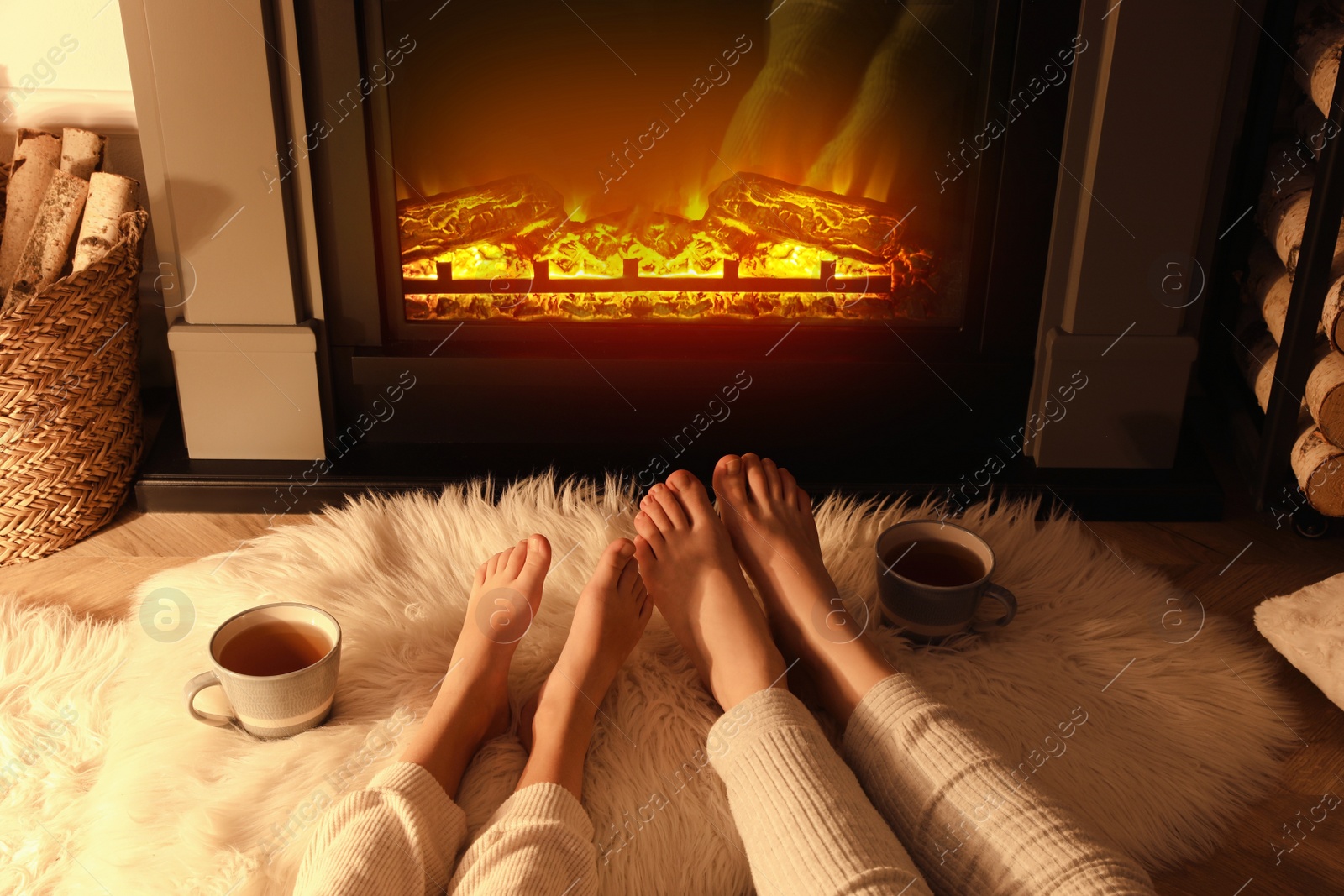Photo of Couple resting near fireplace at home, closeup of legs
