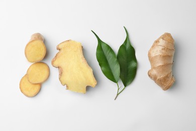 Photo of Fresh ginger with green leaves on white background, flat lay