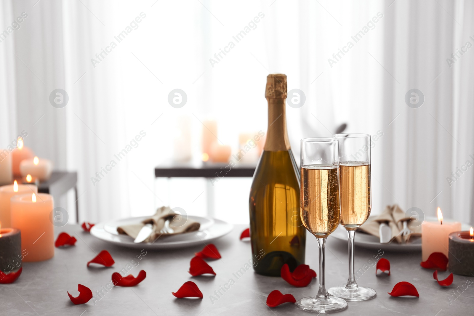 Photo of Romantic table setting with burning candles and rose petals indoors