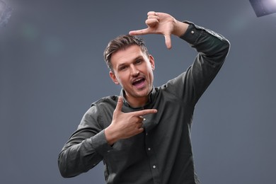 Photo of Casting call. Emotional man showing frame gesture on grey background