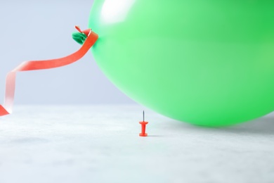 Color balloon and pin on table against white background, space for text