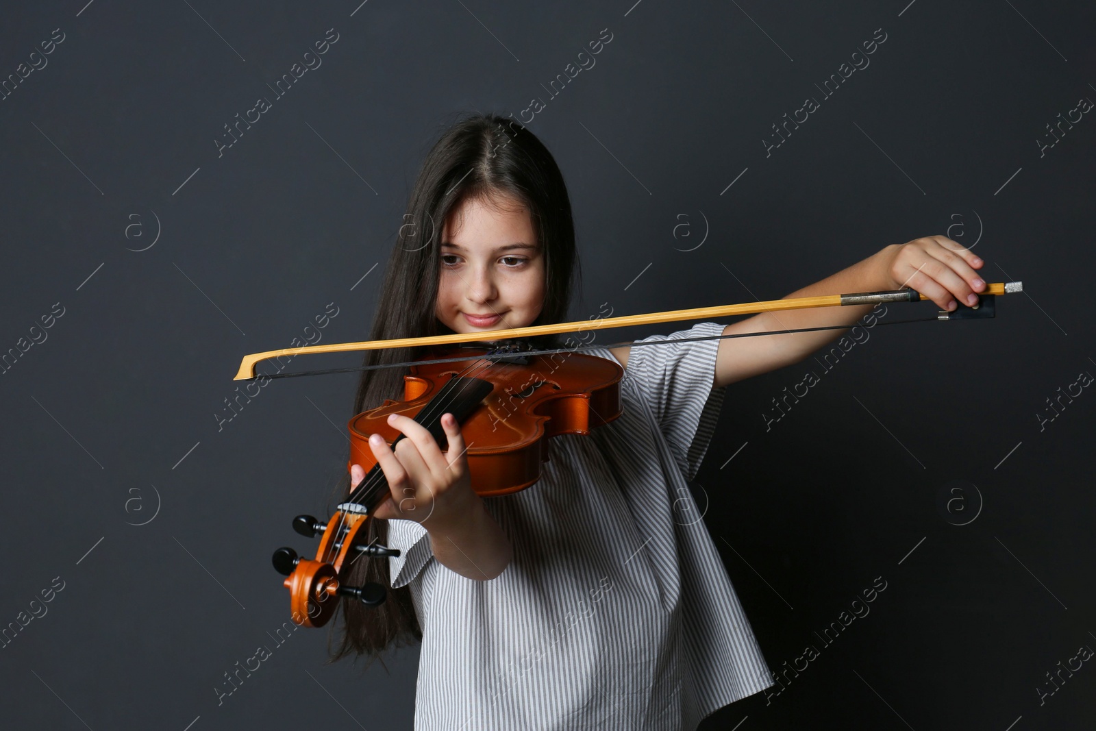 Photo of Preteen girl playing violin on black background