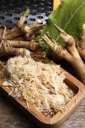 Grated horseradish and roots on wooden table, above view