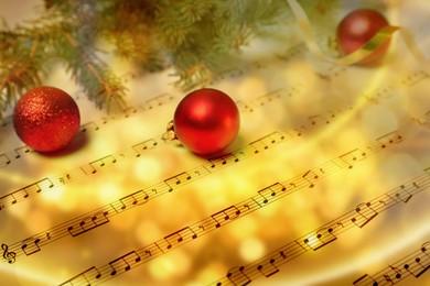 Image of Composition with Christmas balls and fir tree branches on music sheets