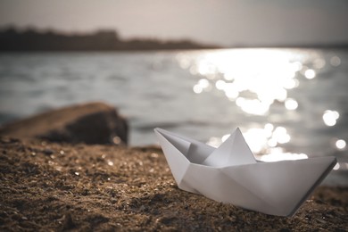 Image of White paper boat near river on sunny day. Retro photo effect
