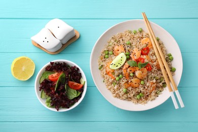 Tasty rice with shrimps and vegetables served on turquoise wooden table, flat lay