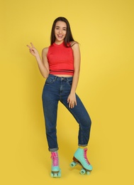 Photo of Full length portrait of young woman with roller skates on color background