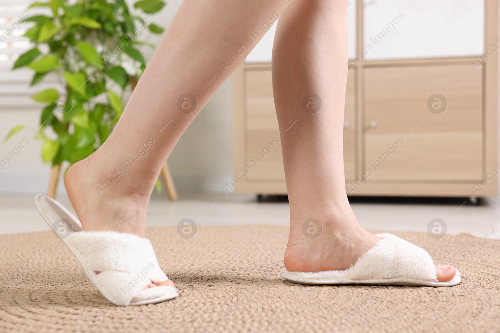 Photo of Woman in white soft slippers at home, closeup