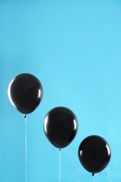 Photo of Black balloons on blue background, space for text. Halloween party