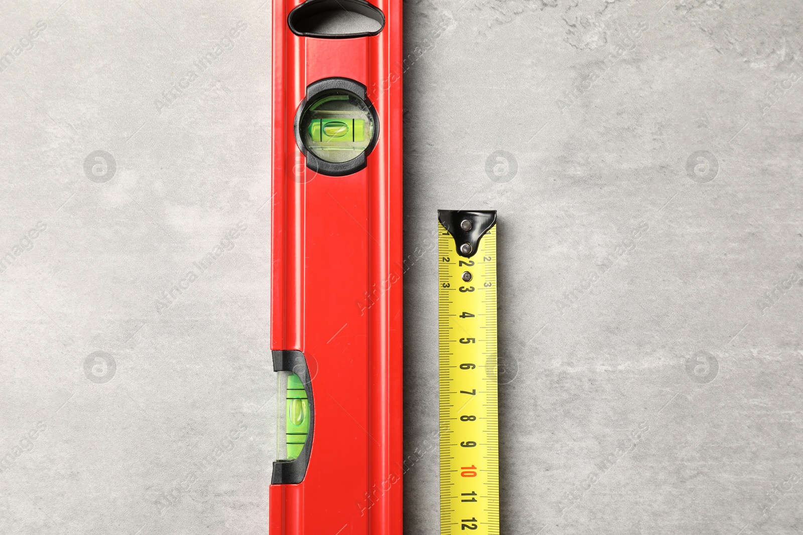 Photo of Building level and tape measure on grey table, top view