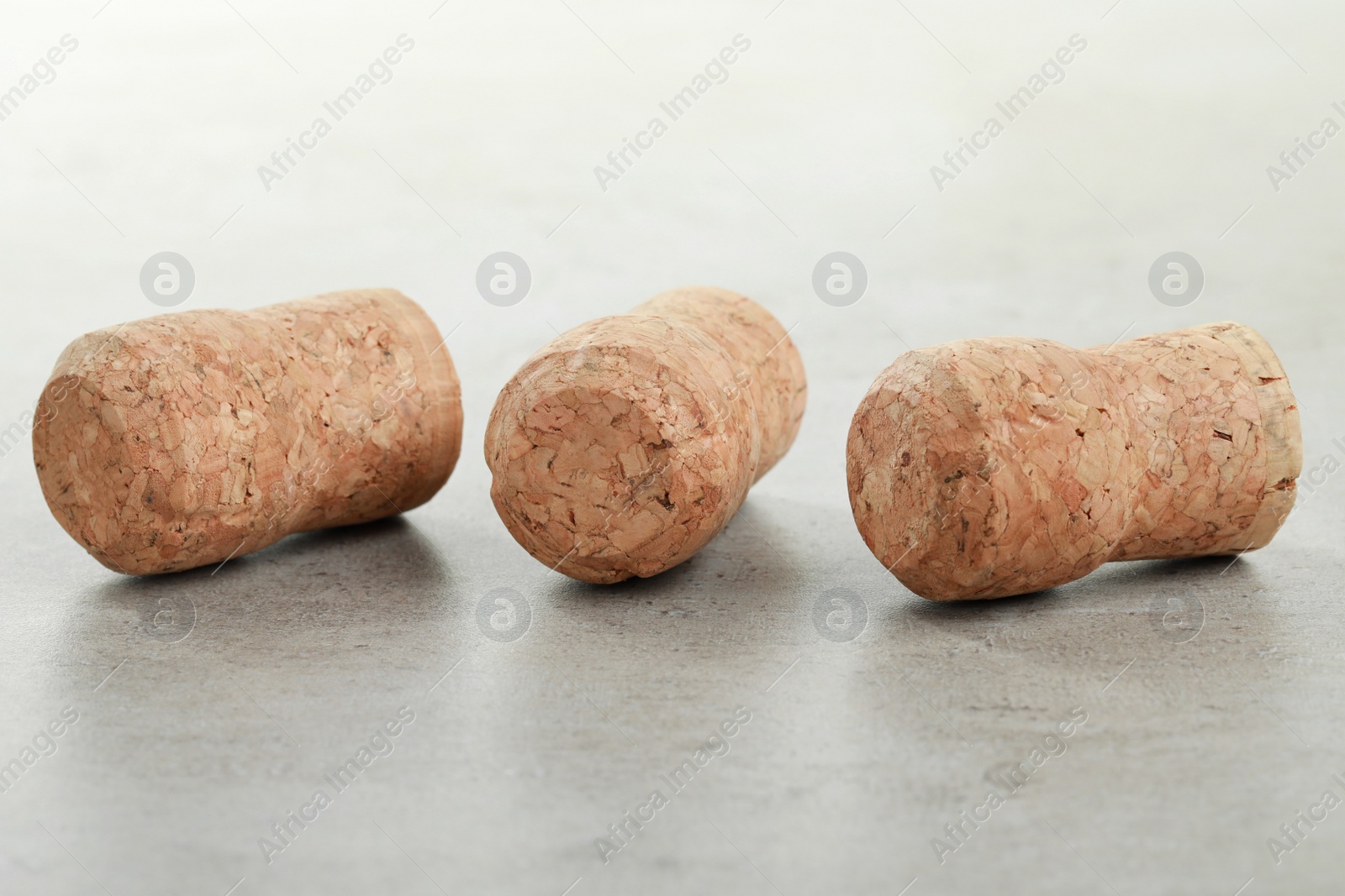 Photo of Corks of wine bottles on light grey table, closeup