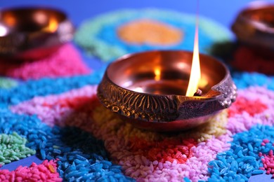Photo of Diwali celebration. Diya lamp on colorful rangoli, closeup