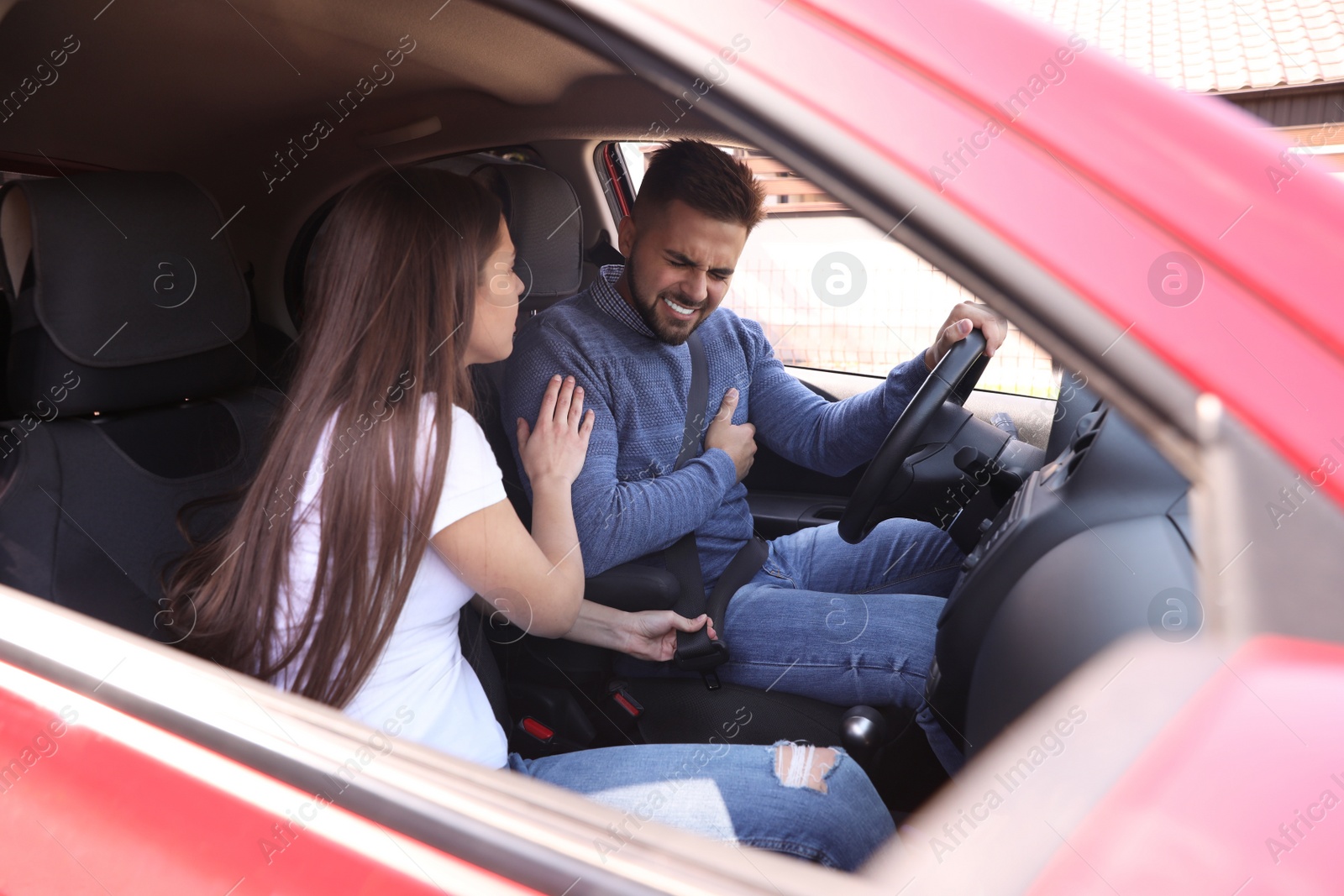 Photo of Young woman and man suffering from heart attack in car