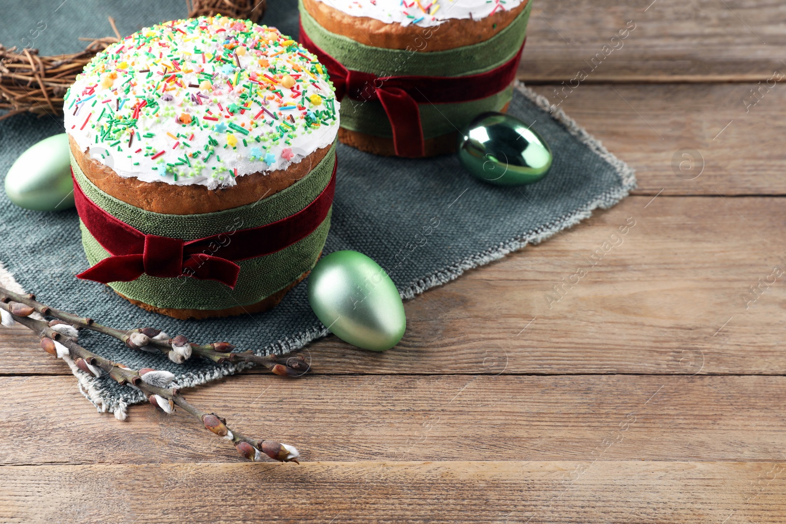 Photo of Traditional Easter cakes, painted eggs and willows on wooden table. Space for text