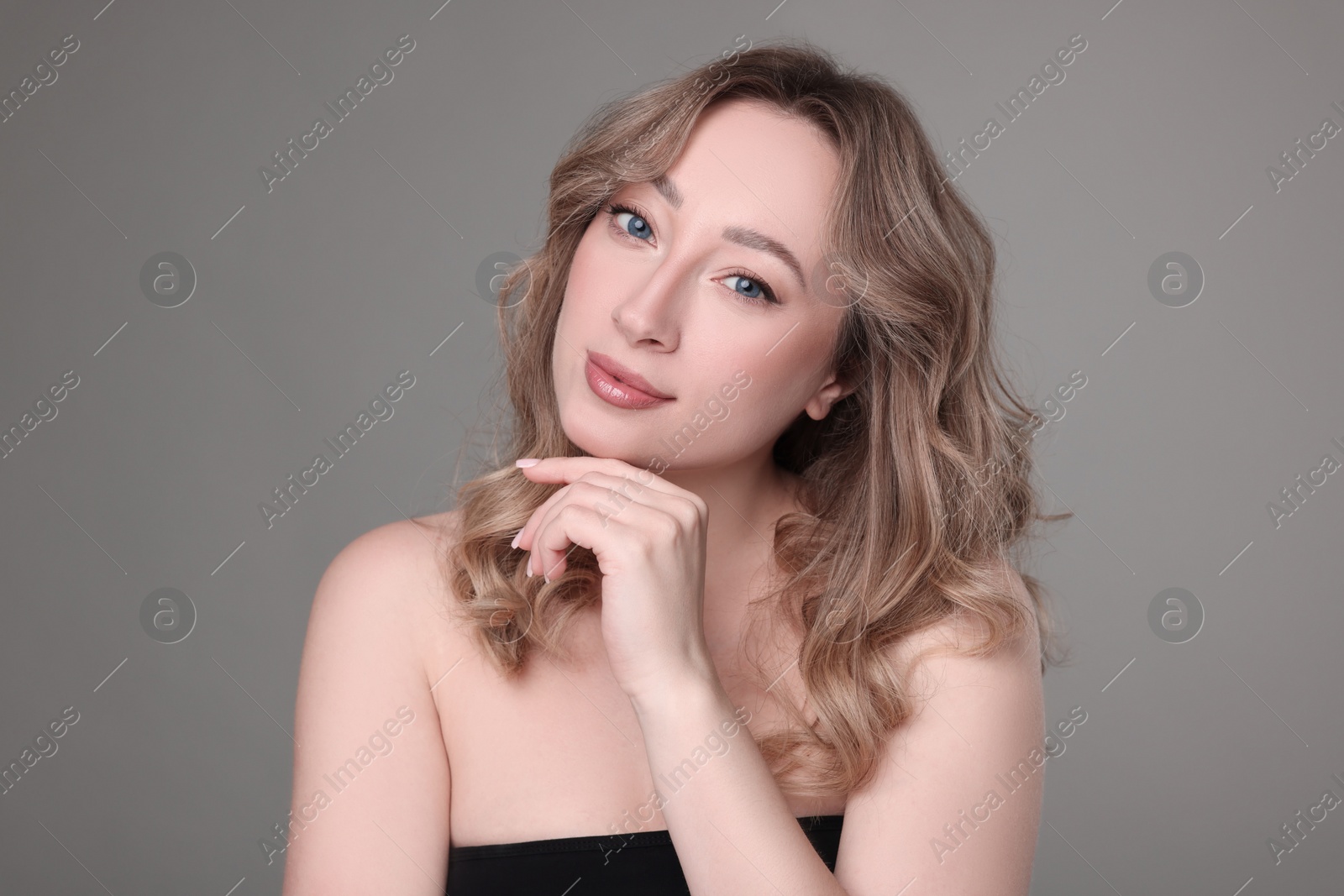 Photo of Portrait of beautiful woman with curly hair on grey background