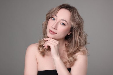 Portrait of beautiful woman with curly hair on grey background