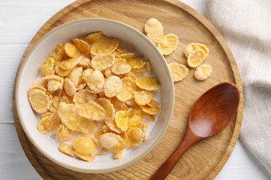 Photo of Tasty cornflakes with milk in bowl served on white wooden table, top view