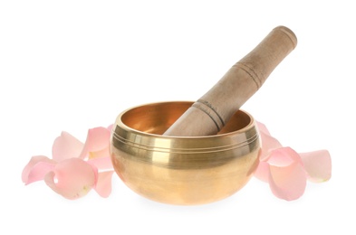 Photo of Golden singing bowl with mallet and petals on white background. Sound healing
