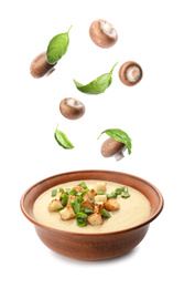 Image of Fresh mushrooms and basil falling into bowl with homemade soup on white background