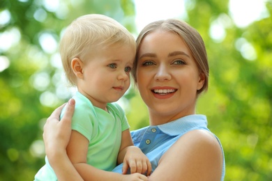 Photo of Young mother with her cute child in green park