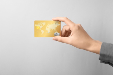 Woman holding credit card on light background