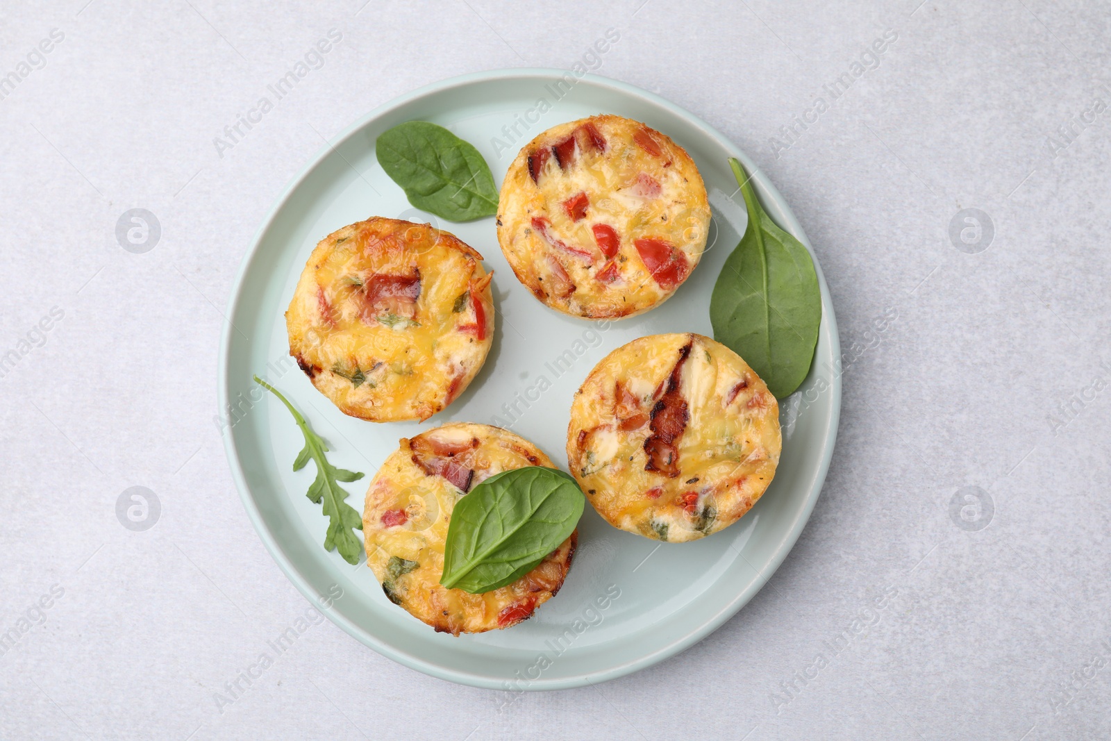 Photo of Freshly baked bacon and egg muffins with cheese on light gray table, top view