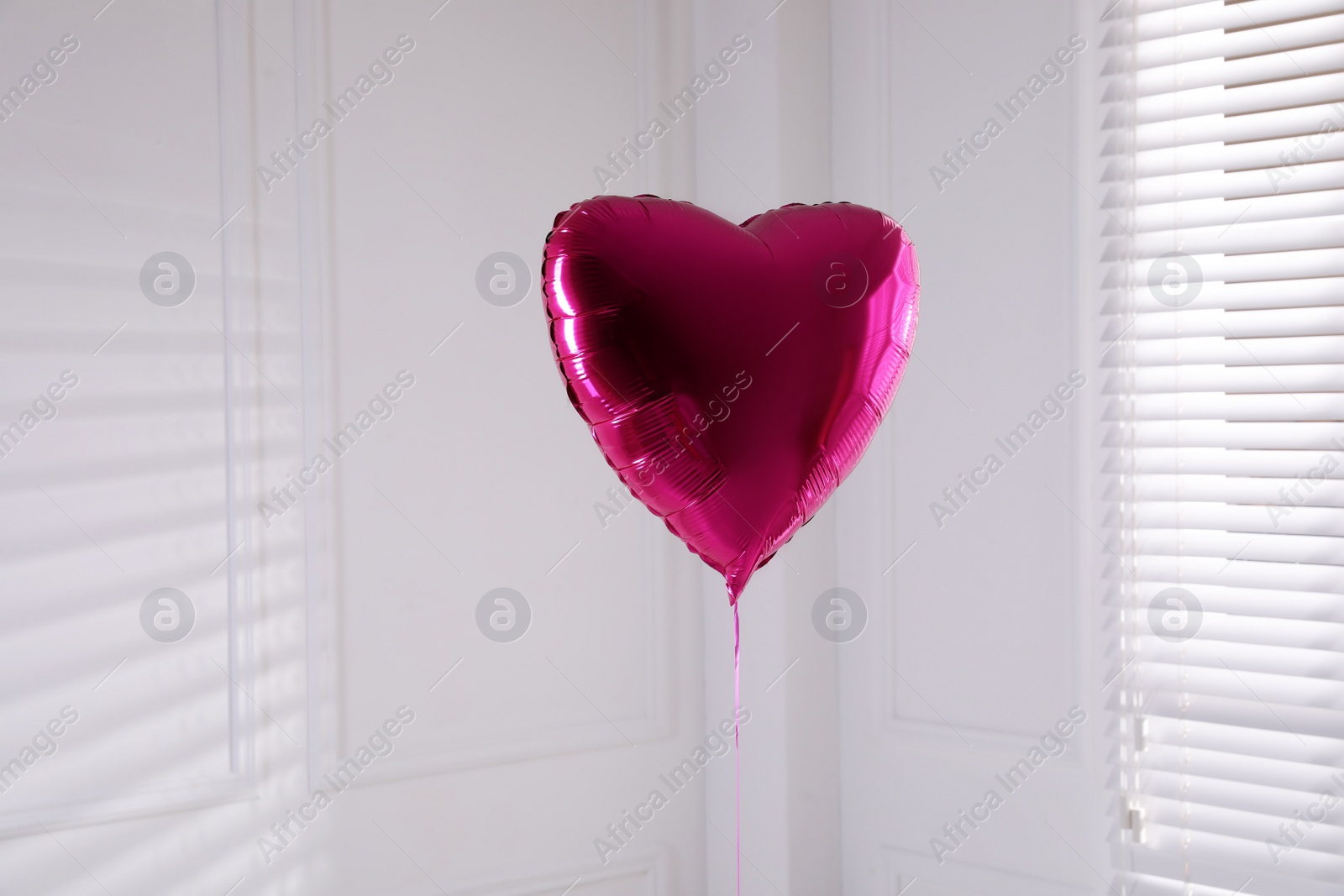 Photo of Festive heart shaped balloon in light room
