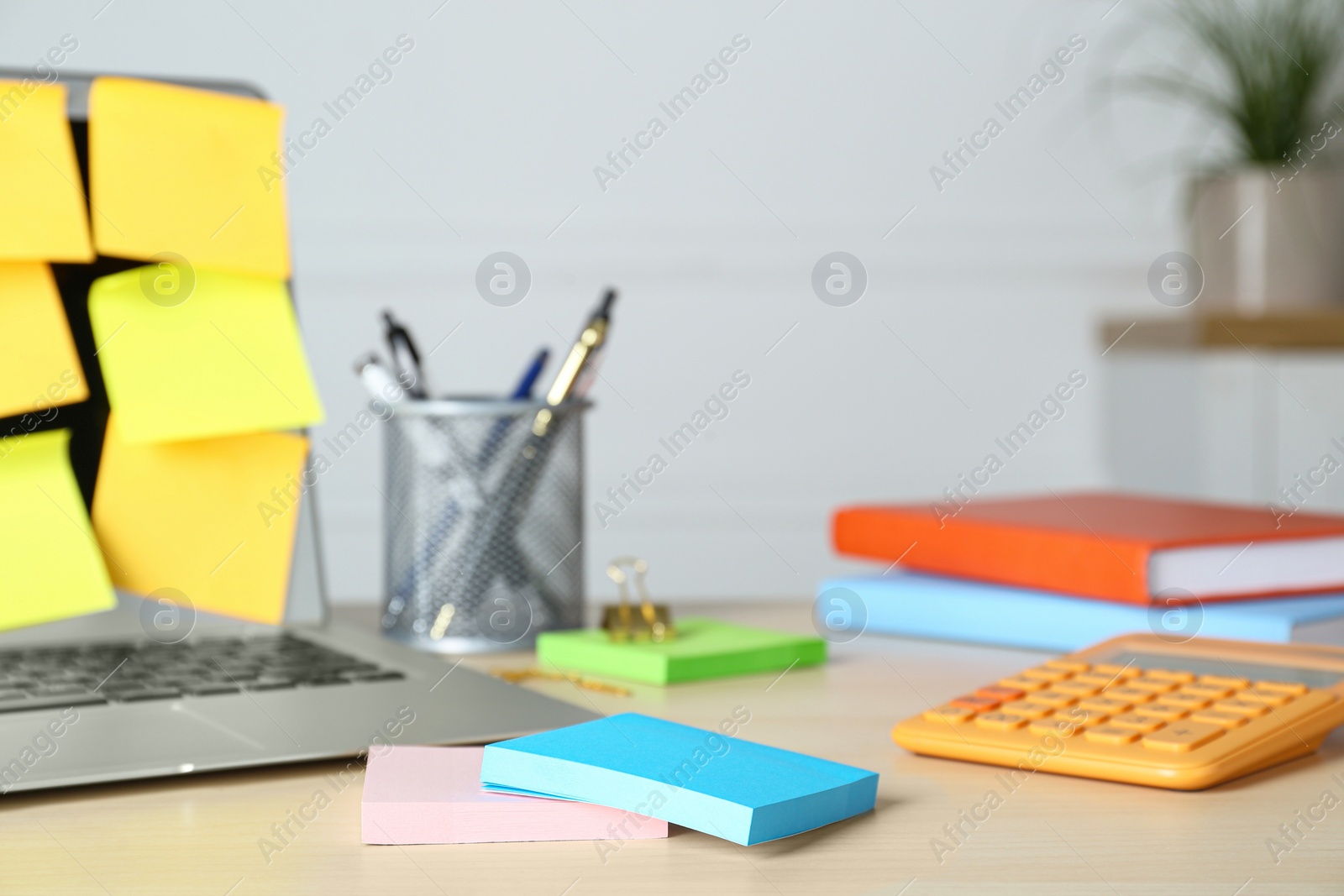 Photo of Colorful sticky notes, laptop and stationery on wooden table