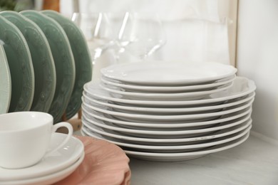 Clean plates, cup and glasses on white marble table in kitchen