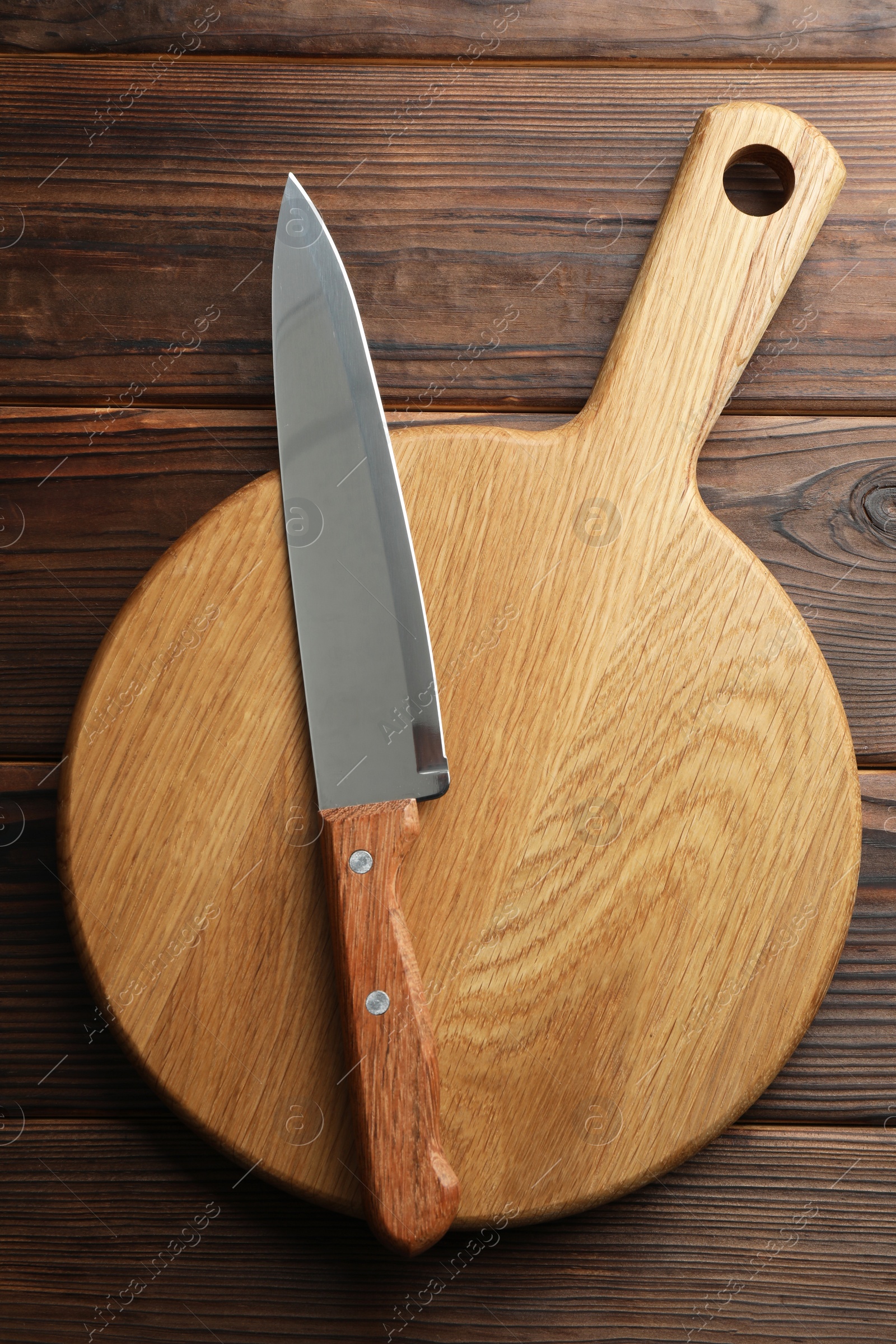 Photo of Knife and board on wooden table, top view