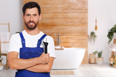 Plumber with adjustable wrench in bathroom, space for text