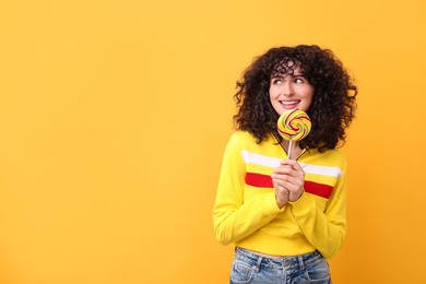 Photo of Beautiful woman with lollipop on yellow background, space for text