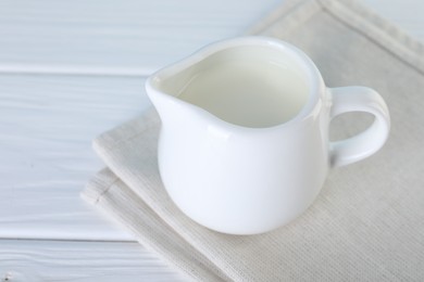 Photo of Jug of fresh milk on white wooden table, closeup