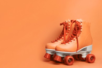 Image of Pair of stylish quad roller skates on orange background. Space for text